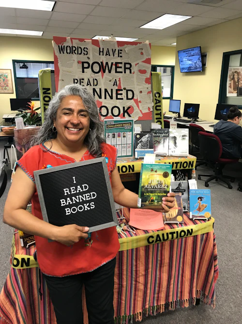 woman stands holding a sign that says "I read banned books."