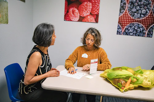 two women discussing healthy food at a table