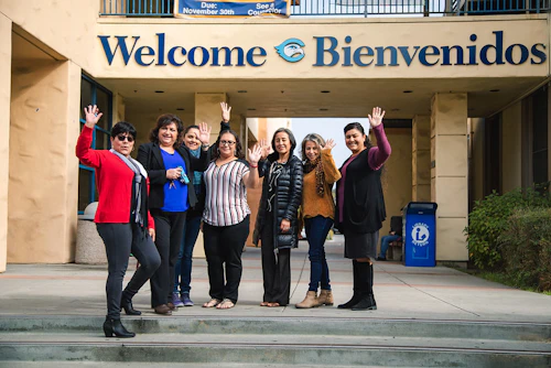 Estudiantes e instructores saludando desde los escalones de la escuela