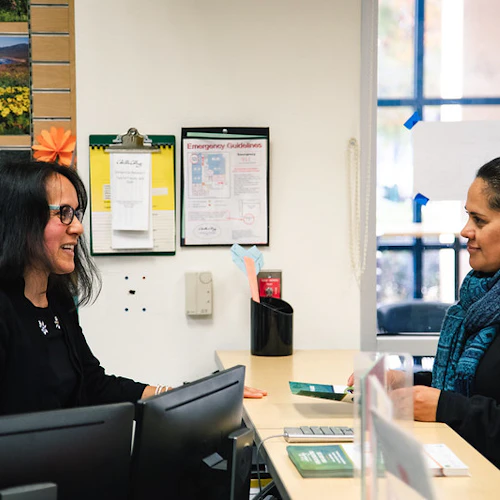 A student and an instructor are speaking at the office desk