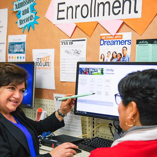 Una mujer que muestra descripciones de cursos a otra persona en la computadora