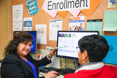 Una mujer que muestra descripciones de cursos a otra persona en la computadora