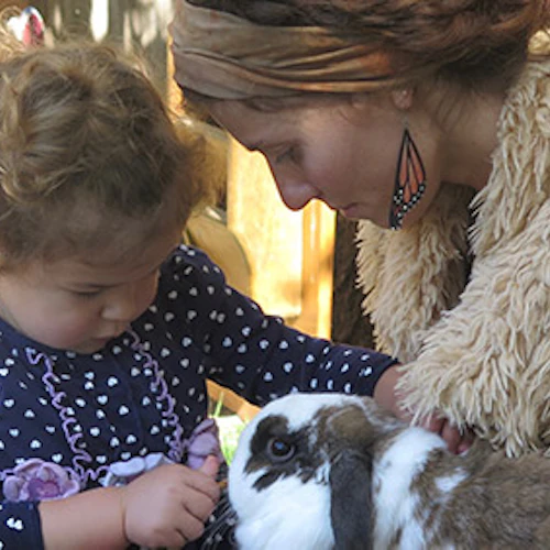 A toddler and teacher playing with an animal