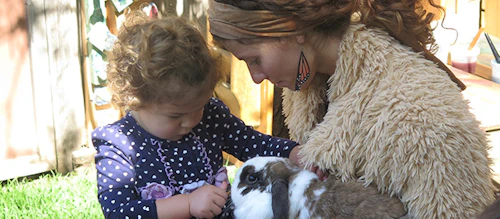 A toddler and teacher playing with an animal
