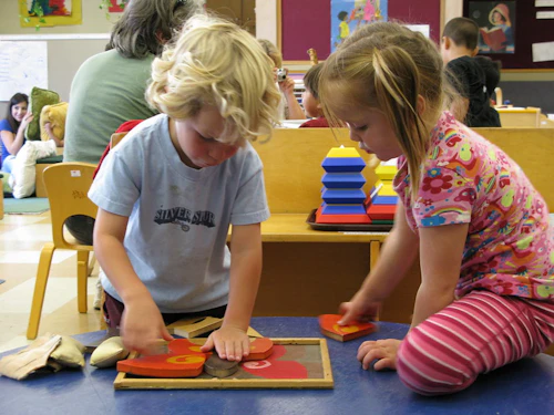 a toddler boy and toddler girl are playing with modeling clay