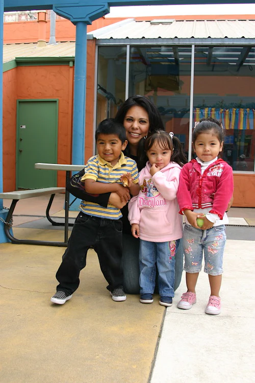 Niños pequeños posando con la maestra en la escuela