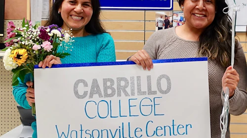 two women holding a sign