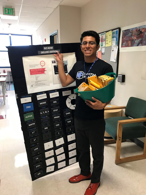 a math tutor stands with a bucket of graphing calculators