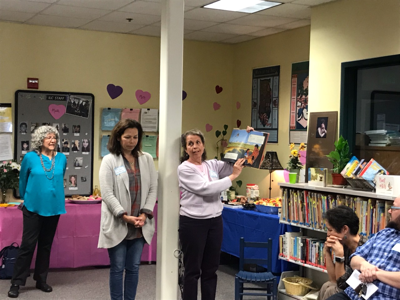 ECE teachers hold up a children's picture book from the library