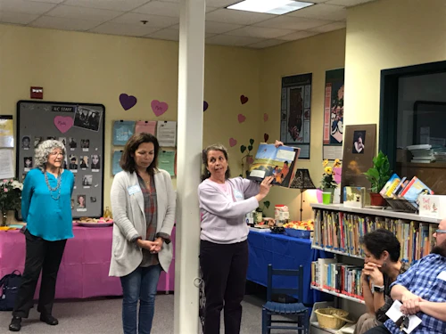ECE teachers hold up a children's picture book from the library