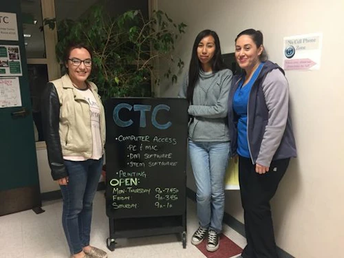 three students standing next to a sign