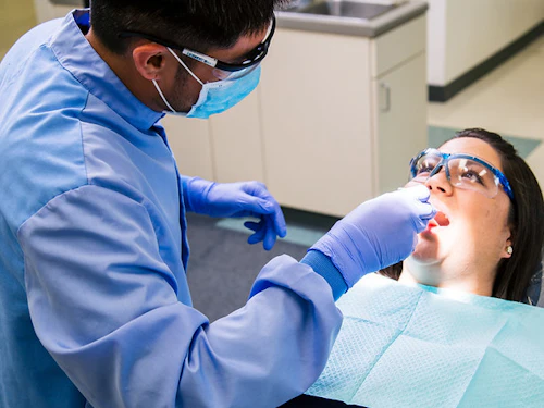 estudiante varón tratando los dientes de una paciente femenina