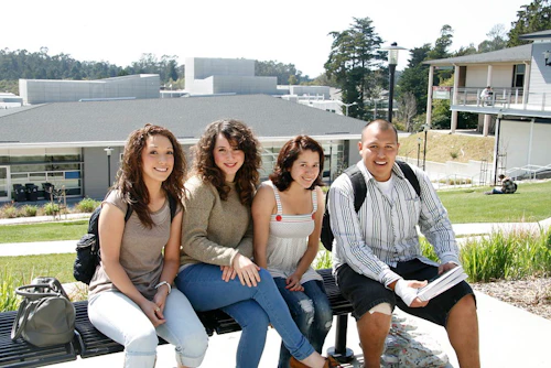 4 estudiantes sentados en un banco en el campus