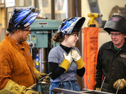 estudiante y profesor de programa de soldadura en aula al aire libre