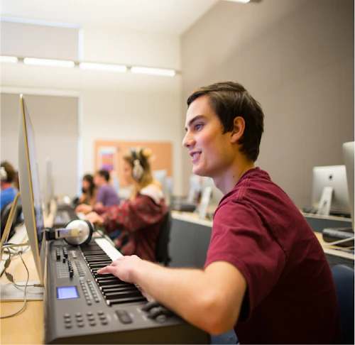 music department male student working with piano keyboard and desktop