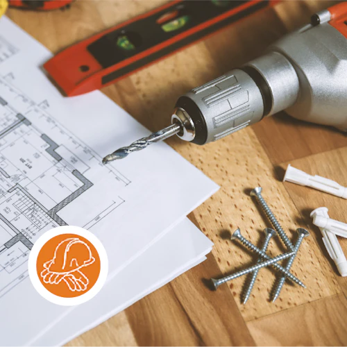 clavos, taladro, nivel y planos de construcción sobre una mesa