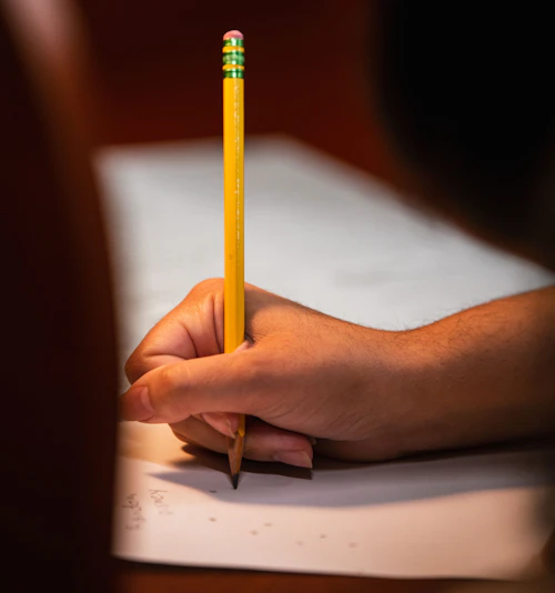 Estudiante escribiendo con lápiz.