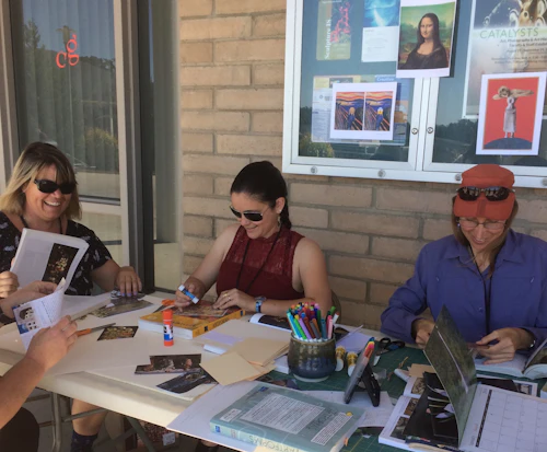 personas sentadas en una mesa haciendo tarjetas