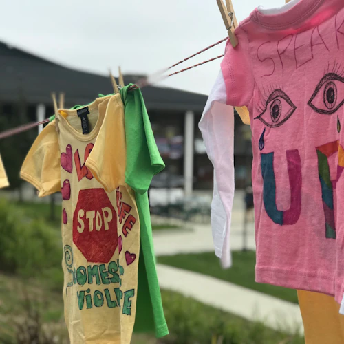 clothesline with several shirts reading "stop domestic violence" and speak up"