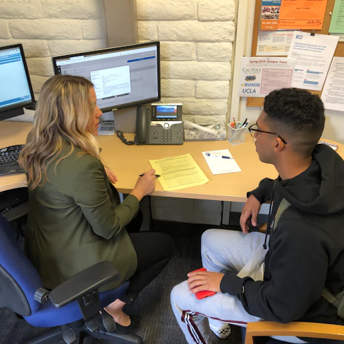 Decorative Image: Counselor working with a student sitting at a desk