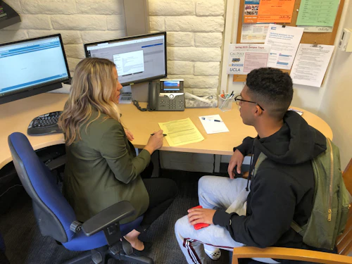 Decorative Image: Counselor working with a student sitting at a desk