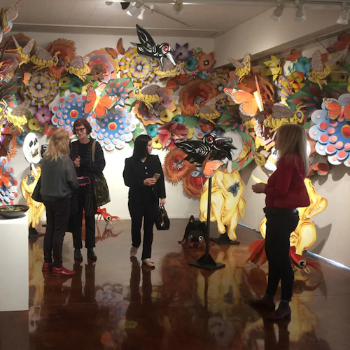 people milling about an installation of flowers made out of spray painted cardboard