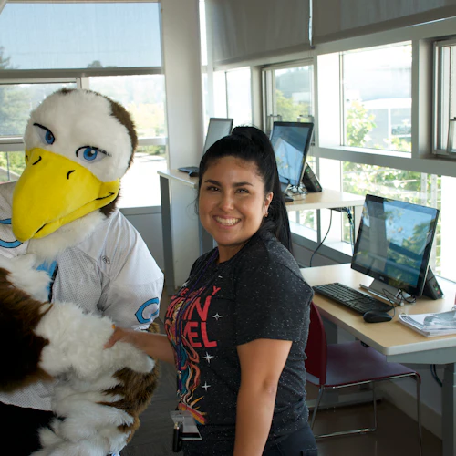 Sammy the Seahawk standing with a student