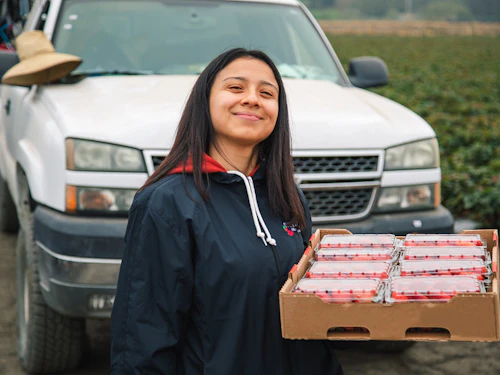 A female community health worker holding strawberries