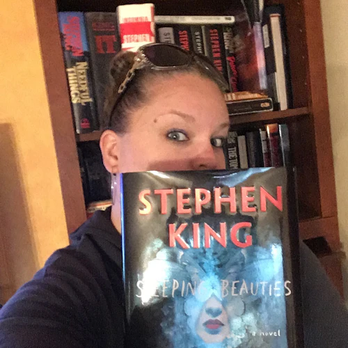 Michaela peeking from behind a Stephen King and Owen King book.