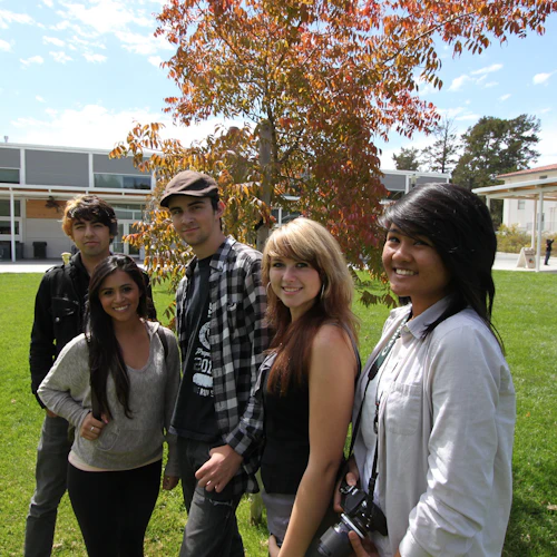 group of smiling students smiling standing outside on a lawn