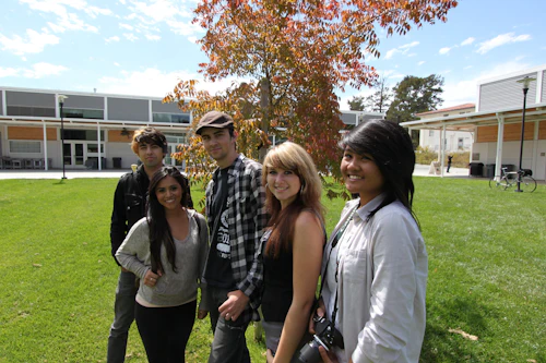 group of smiling students smiling standing outside on a lawn