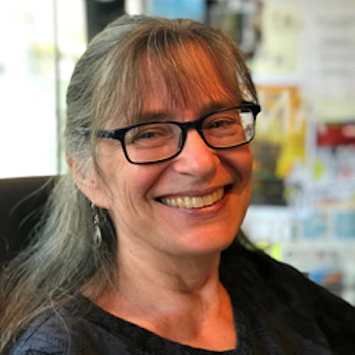 Audrey Blumeneau, wearing dark rimmed glasses, smiling