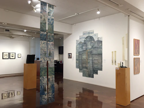 installation view with cyanotype scroll hanging in foreground and multi-print painted gelatin silver prints in background