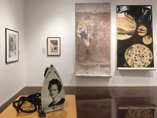 installation shot with iron with image of 60s woman transferred on surface and lumen scrolls hanging in background