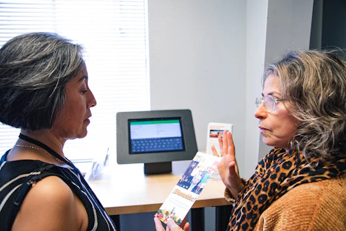 Two women talking near a computer about the program