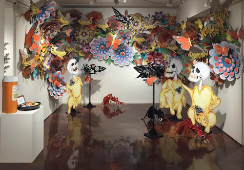 fantástica instalación colorida de cartulina pintada a espray y relieve que representa flores, abejas y esqueletos