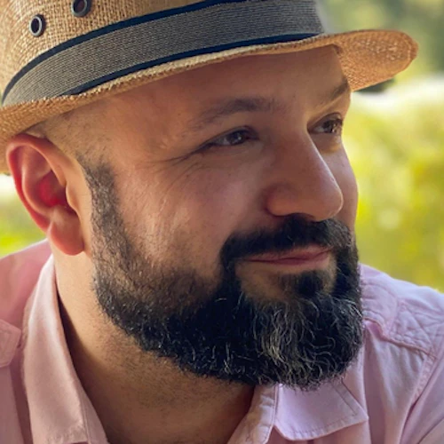 John Robertson con una barba negra entrecana y un sombrero de paja al aire libre.