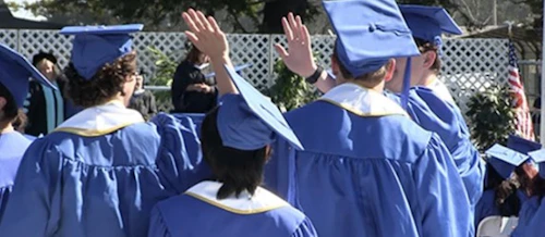 students at grad ceremony "high-fiving" each other