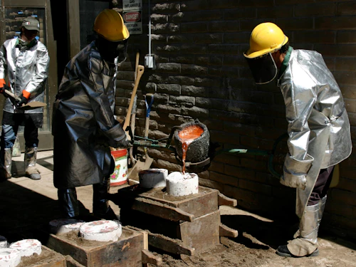 student pouring molten metal into mold
