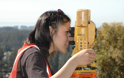 Engineering student looking through a surveying tool