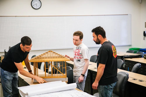 Estudiantes revisando los planos de diseño de un edificio