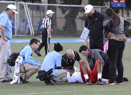 Athletic Trainers on the field attending to an injured athlete