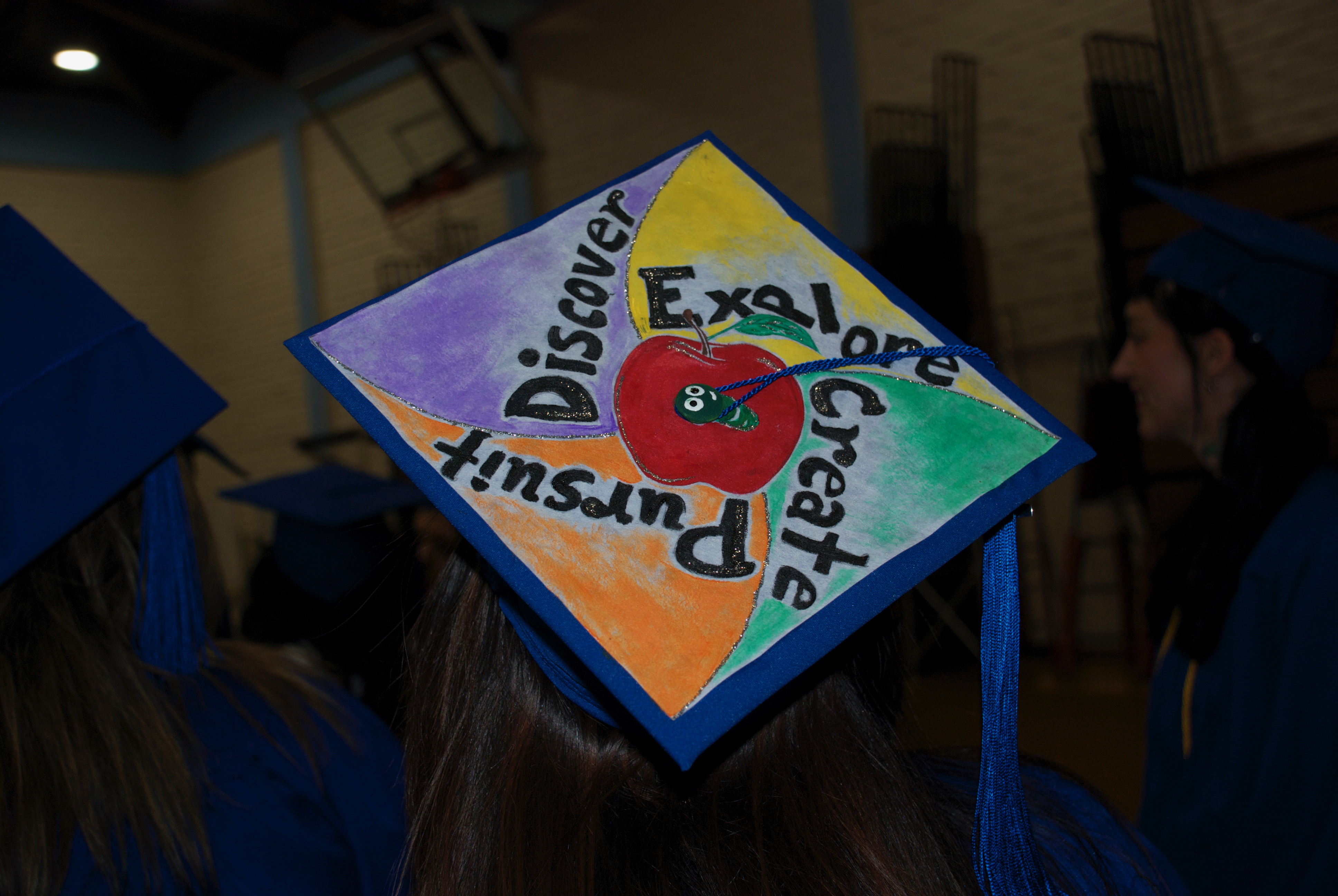 mortar board at graduation painted with the words: discover. explore, create and pursue