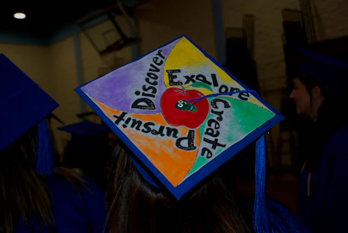 mortar board at graduation painted with the words: discover. explore, create and pursue