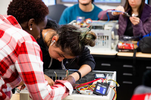 two students working on a circuit board in class