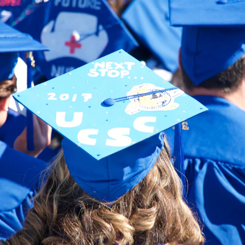 student wearing a mortar board with "UCSC" decorating the top