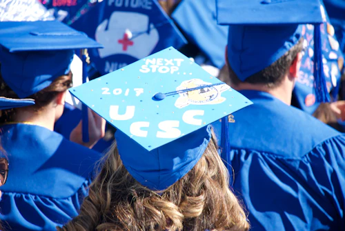 student wearing a mortar board with "UCSC" decorating the top