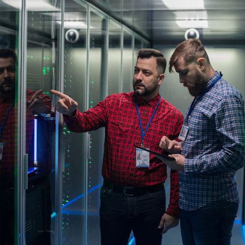 two male adults looking at computer servers