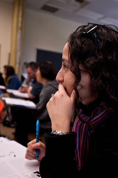 estudiante con cabello largo y rizado tomando apuntes en clase