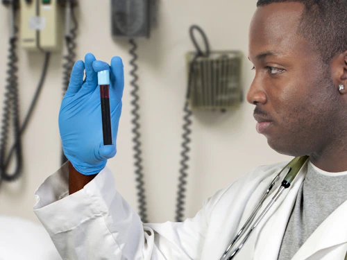 Flebotomista varón sosteniendo un tubo de ensayo con sangre